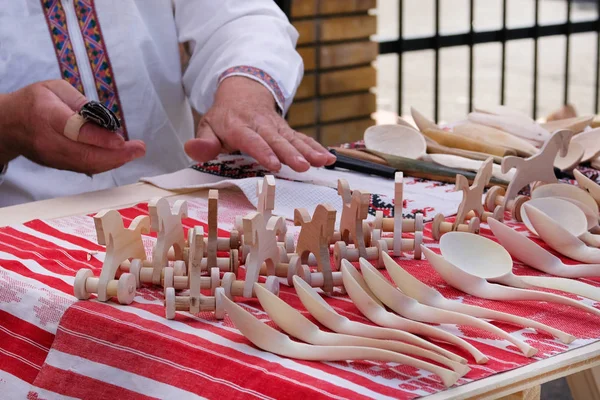 Řemeslník nabízeného k prodeji dřevěné ručně vyrobené hračky a lžíce. Koncepce národní řemesla. — Stock fotografie