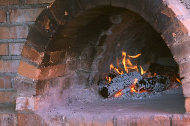 Yemek pişirmek için eski geleneksel tuğla taş fırın içinde ateş yakar. Woods ve alevler içinde fırın burning.