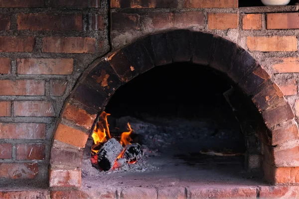 Fire burns in old traditional brick stone furnace for cooking. Cooking in a wood-fired oven. — Stock Photo, Image