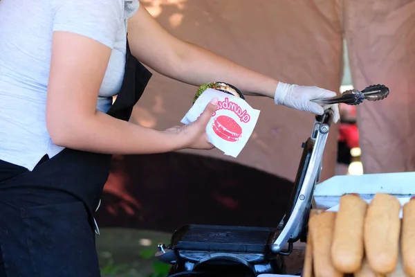 Chica está preparando hamburguesa en la parrilla. Comida callejera y concepto de cocina al aire libre — Foto de Stock