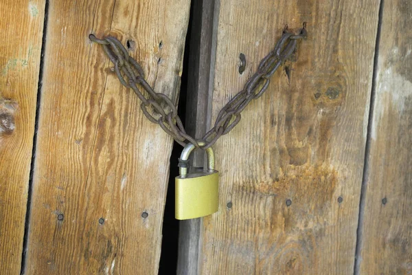 Lock on the wooden gates. Worn-out wooden plank gates. Concept of what goes on behind closed doors.