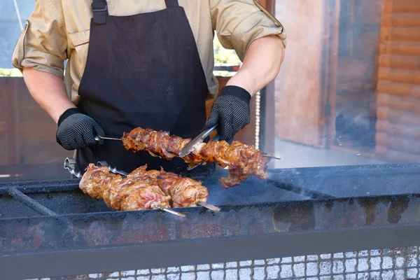 O homem está a fritar carne numa fogueira. comida de rua e conceito de cozinha ao ar livre . — Fotografia de Stock