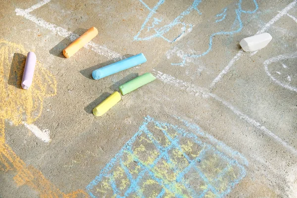 Buntstifte in lila, blau, grün, gelb, weiß auf dem Bürgersteig. Mit Buntstiften bemalte Bodenfliesen im Park. Freizeitkonzept für Kinder. — Stockfoto