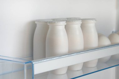 Yoğurt açık boş buzdolabı rafındaki beyaz şişe. Fermente gıda kavramı.