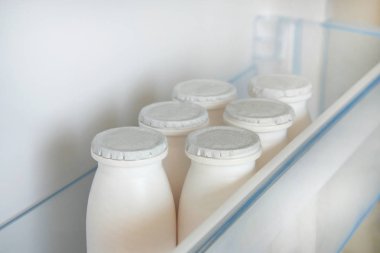 Kefir açık boş buzdolabı rafındaki beyaz şişe. Fermente gıda kavramı.