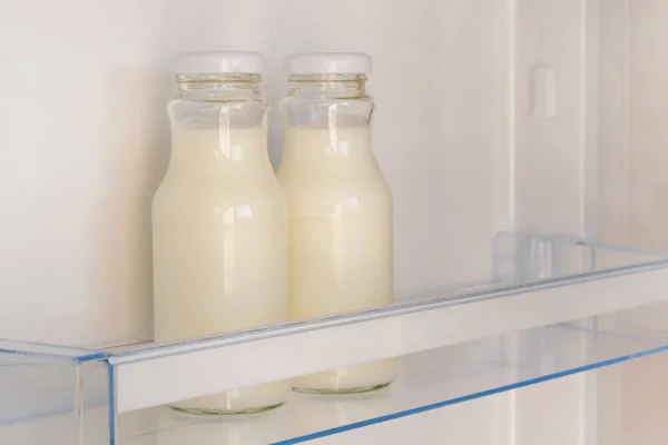 Yogurt in white bottles on shelf of open empty fridge. Weight loss diet concept. Fermented food.
