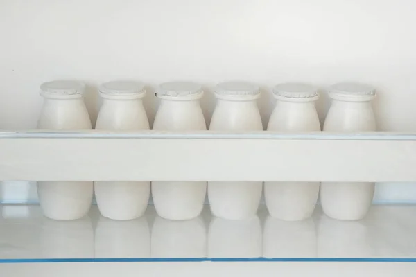 Garrafas brancas de iogurte na prateleira do refrigerador vazio aberto. Conceito de dieta de perda de peso. Vista horizontal . — Fotografia de Stock