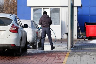 Adam araba yıkamacıda arabasını yıkar. Sabun köpük Self-Servis Oto yıkama, temizlik.