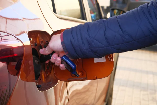 Male hand opens fuel fill in car. Fueling car with petrol pump at gas station. Petrol station. Gasoline and oil products. Close up. — Stock Photo, Image