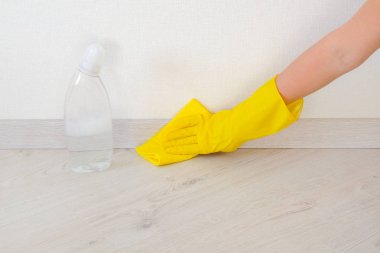 Sarı kauçuk koruyucu eldiven mikro fiber bez ile çalışan elinde zemin ve Süpürgelik siliyor. Ofis, ev temizlik kavramı.