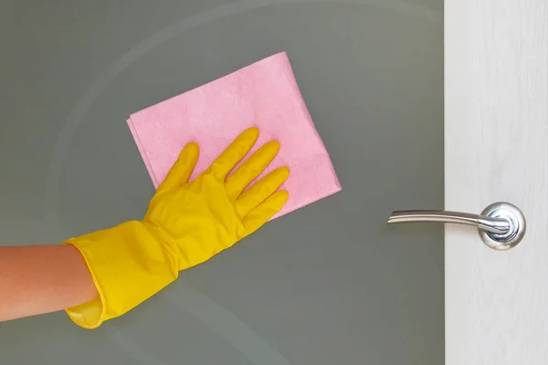 Ticari temizlik şirket kavramı. Cam kapı elinde kauçuk koruyucu eldiven pembe mikrofiber bezle silerek.