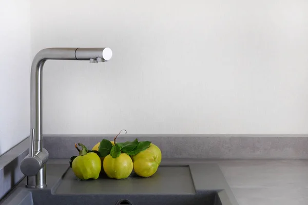 Κίτρινο ζουμερός μήλο κυδώνι δίπλα στο νεροχύτη στην κουζίνα. Σύγχρονη πάγκο με νεροχύτη στην κουζίνα. Πλύσιμο λαχανικών έννοια. Χώρο αντίγραφο. — Φωτογραφία Αρχείου