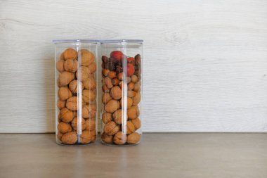 Fındık (ceviz ve fındık) ve kuru kırmızı meyveler büyük cam kavanoz kaplarda mutfak gri tablo üzerinde durmak. Vejetaryen sağlıklı yiyecekler kavramı.