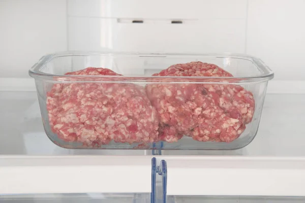 Rauw gehakt in glas container is op plank in open koelkast. Ingrediënt voor het koken van vleesgerechten. — Stockfoto