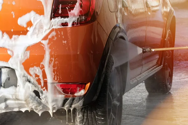 Carro está limpando com sabão suds em auto-serviço de lavagem de carro. Salpicos de água em torno do carro e água ensaboada corre para baixo . — Fotografia de Stock