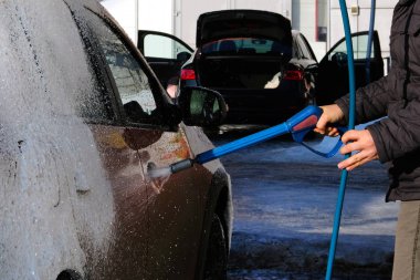 Adam açık havada araba yıkamacıda turuncu arabasını yıkar. Sabun köpük Self-Servis Oto yıkama, temizlik.