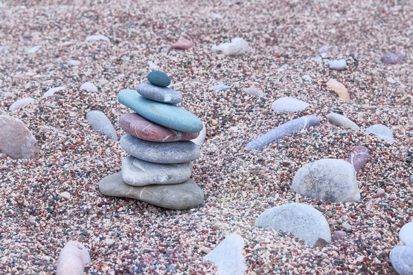 Balanced stones on sea beach. Sand on beach. Pyramid of pebbles. Harmony, balance and relax concept.