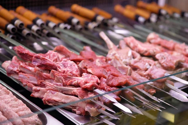 Halve afgewerkte vleesproducten op een spies in winkels koelkast. Vlees steaks, ribben klaar voor het roosteren in brand. Horeca concept. — Stockfoto