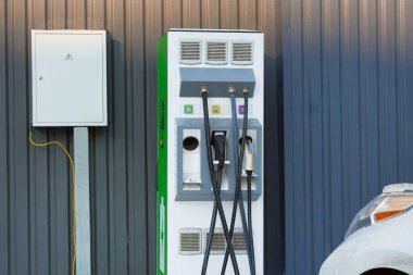 Eko Dostu taşıma kavramı. Demir metal çit park yerinde yakınındaki yüklü araba elektrik şarj istasyonu.
