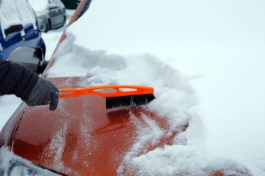 Adam turuncu kar arabadan temizler. Fırça el mans. Arabanın ön cam. Kış, kar, araç.