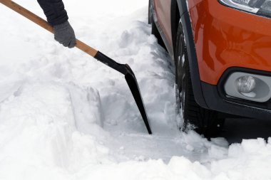 Adam kürek ile araç park yerinde etrafında kar kış kar yağışı sonra temizler. Elinde kürek. Araba sürücüleri kış sorunları.