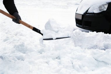 Araba sürücüleri kış sorunları. Adam kürek ile araç park yerinde etrafında kar kış kar yağışı sonra temizler. Elinde kürek.