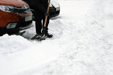 Elinde kürek. Adam kürek ile araç park yerinde etrafında kar kış kar yağışı sonra temizler. Araba sürücüleri kış sorunları.