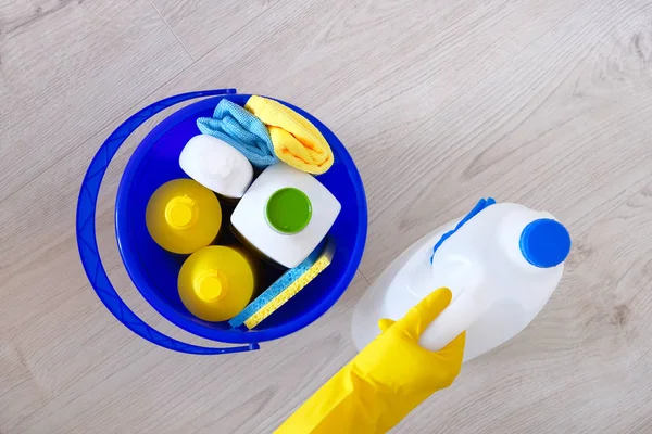 塑料瓶、海绵、蓝色家用水桶中的洗涤剂。手在黄色橡胶手套。服务理念。顶部视图。扁平. — 图库照片