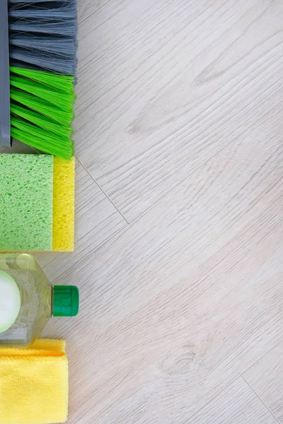 Set of green cleaning products on wooden background. Detergent in plastic bottle, sponges and brush. Service concept. Top view. Close up.