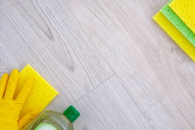 Temizlik seti araçları ve ürünün hafif ahşap arka plan ile. Sarı kauçuk koruyucu eldiven mikro fiber bez ile el. Üstten Görünüm.