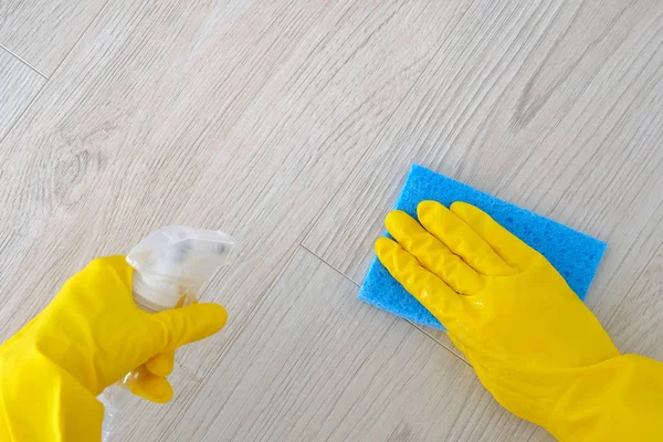 Hand in yellow rubber protective glove with micro fiber cloth and detergents in spray, copy space. Service concept. Top view. Flat lay.