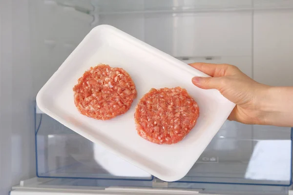 Rauwe kip Burger in container is op plank in open koelkast. Ingrediënt voor het koken van vleesgerechten. Ongekookt gehakt vlees. — Stockfoto