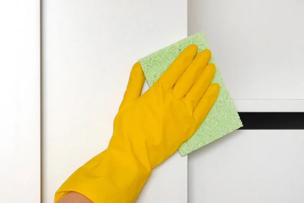 A mão na luva protetora de borracha com pano está limpando o armário no quarto. Limpando prateleira branca do pó. Limpeza ou limpeza regular . — Fotografia de Stock