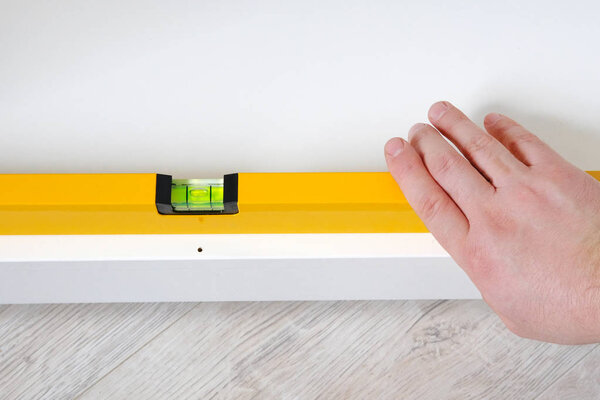 Repairs in house or apartment. Male hand repairing white furniture with level in house or apartment, closeup. Diy repairs.