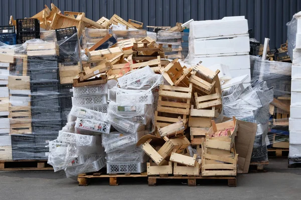 Stapels houten en plastic dozen bij magazijn in winkel werf. Gebruikte dozen en containers voor transport producten per vrachtwagen. Vracht en verzending in winkels. — Stockfoto