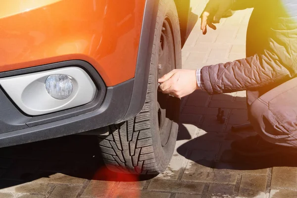 Wheel balancing or repair and change car tire. Automobile maintenance concept. Damaged tyre in orange car. Sunlight. — Stock Photo, Image