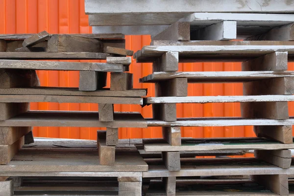 Színes, durva fából készült rakodólapok zsetonszáma a raktárban ipari udvarban. Asztalok narancssárga háttérrel. Teher-és szállítási koncepció. — Stock Fotó