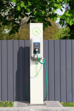Elektrik şarj istasyonu. Çevre dostu ulaşım konsepti. Şarj istasyonunun önünde oturum açın. Dikey görünüm.