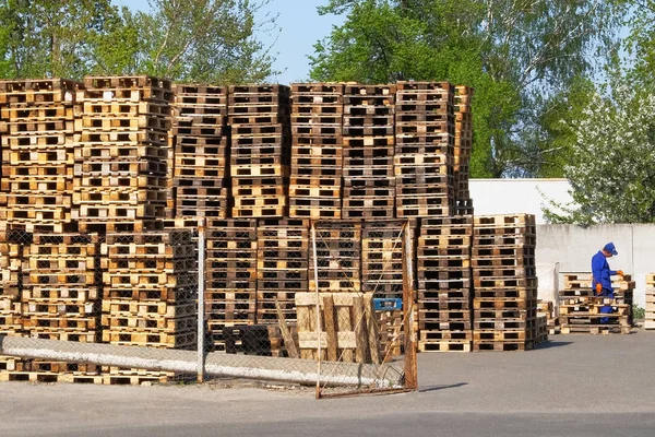 Stacks of lot rough wooden pallets at warehouse in industrial yard. Pallets background. Cargo and shipping concept.