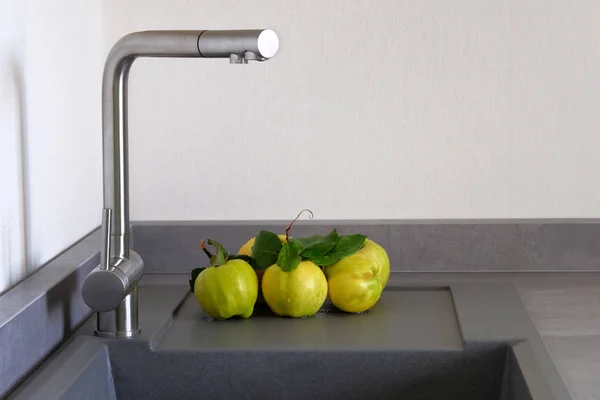 Coing pomme à côté de l'évier dans la salle de cuisine. Comptoir moderne avec évier dans la cuisine. Concept de lavage des fruits. Espace de copie . — Photo