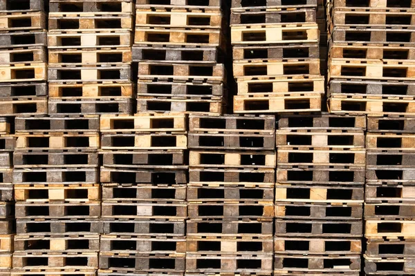 Pallets achtergrond. Stapels van ruwe houten pallets in magazijn in industriële werf. Vracht-en verzend concept. — Stockfoto