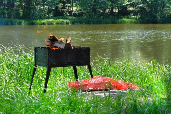 Grill. Grillen in der Natur. Holzfeuer zum Grillen vorbereitet. Grillsaison in Flussnähe. Sonne. — Stockfoto