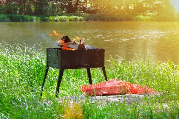 Grill. Picknick. Grillen in der Natur. Holzfeuer zum Grillen vorbereitet. Grillsaison in Wassernähe. Sonnenlicht. — Stockfoto