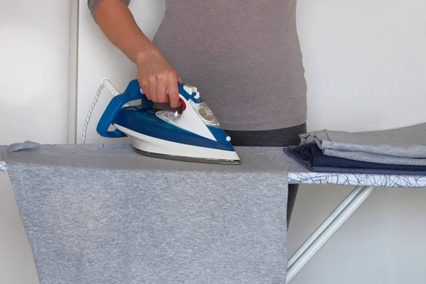 Clothing ironing at home. Girl is ironing garments at home. Female hand is ironing clothes, close up. — Stock Photo, Image