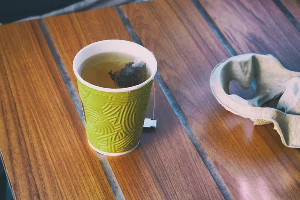 Tea bag in paper cup. Takeaway. Morning breakfast in cafe. Toned image.