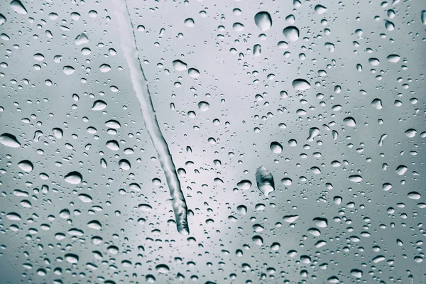 Rain drops visible on window. Winter raining day in city. Rainy day with dramatic weather, in selective focus. — Stock Photo, Image