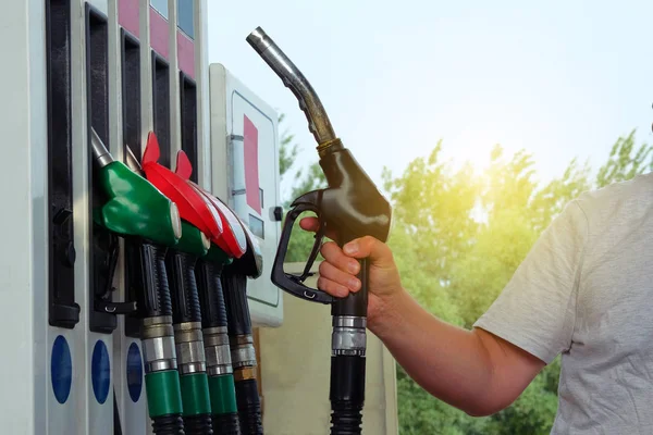 Man fills up his car with a gasoline at gas station. Petrol station pump. To fill car with fuel. Gasoline and oil products concept. Sunlight.