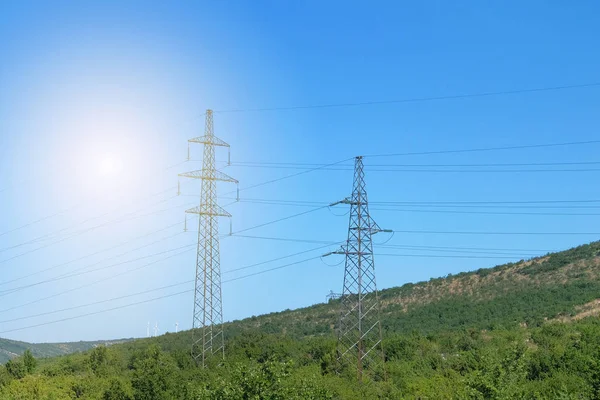 Elektrické vysílání pylonů proti modré obloze. Přenosová linka elektřiny pro venkov v horách. — Stock fotografie