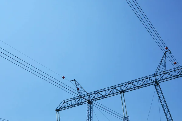 Elektrická tyč s vysokým napětím. Elektrická tyč proti modrému nebi. Přenosová vedení elektřiny. — Stock fotografie