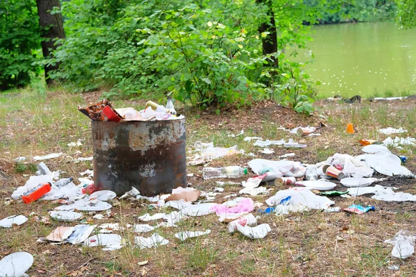 Verontreiniging van de natuur met vuilnisbak. Plastic en papier Prullenbak ligt in het opruimen in het groene bos. Milieuvervuiling concept. — Stockfoto